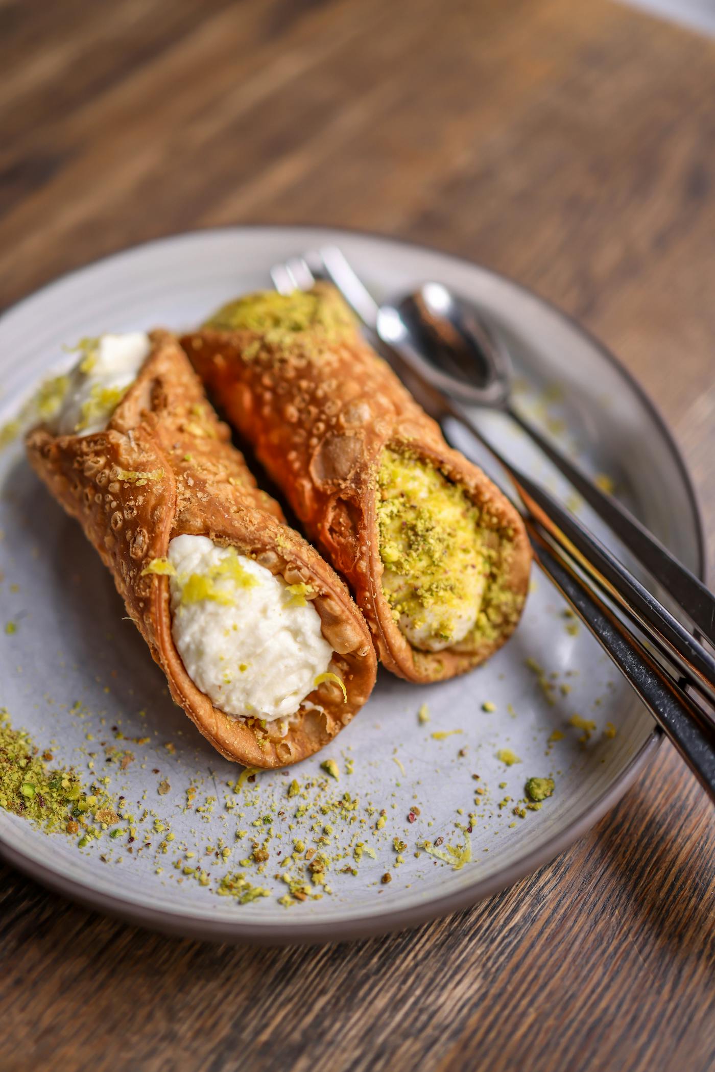 Cannoli siciliens fraîchement garnis, saupoudrés de pistache, sur une assiette