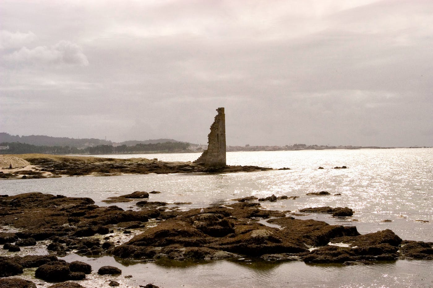 Ruines antiques en pierre sur un littoral mediterraneen rocheux sous un ciel dramatique